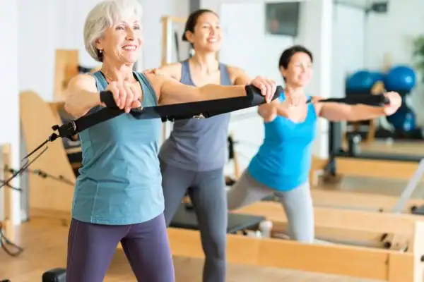 Toning Arms After 60: Empowering Womens Fitness Through Effective Weight Training 2 older woman doing weight training Doncaster and resistance in the gym to tone upper arms